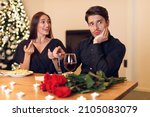 Small photo of Bad Date Concept. Young Millennial Couple Having Unsuccessful Blind Date In Restaurant, Funny And Handsome Disappointed Shoked Man Feeling Embarrassment Listening To Excited Woman Talking