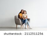 Small photo of Look There. Amazed Mom And Her Little Daughter Sitting In Armchair And Looking Up Above Their Heads With Excitement, Interested Middle Eastern Mother And Female Kid Emotionally Reacting To Offer