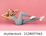 Small photo of Weight Loss Concept. Smiling Sportive Young Woman Doing Side Bicycle Crunches Bringing Elbow Toward Knee With Raised Leg On Floor Isolated Over Pink Studio Background. Pilates And Warm Up Concept