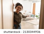 Small photo of Welcome To My Home. Joyful Millennial Black Lady Opening Door And Gesturing Inviting To Come In Standing Indoors, Smiling To Camera. Real Estate Owner. Hospitality Concept