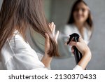 Haircare. Young Female Applying Hair Spray While Standing Near Mirror In Bathroom, Unrecognizable Millennial Woman Testing New Hairstyle Product At Home, Selective Focus On Her Reflection