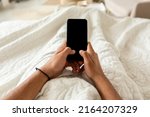POV Of Unrecognizable Guy Holding Cellphone With Empty Screen Using Application And Texting Lying In Bed In Bedroom At Home. Great App For Your Smartphone, Gadgets Lifestyle Concept. Cropped