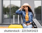 Canceled or delayed flight, difficulties while travelling. Upset young woman tourist waiting for flight at airport, holding documents, phone, touching her head, feeling stressed, looking at copy space