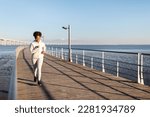 Active Lifestyle. Happy Young African American Woman In Sportswear Jogging Outdoors, Athletic Black Millennial Lady Running On Wooden Pier Near Sea, Enjoying Training Outside, Copy Space