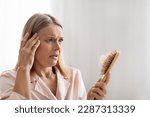 Small photo of Shocked Mature Woman Looking At Brush Full Of Fallen Hair While Making Beauty Routine At Home, Worried About Hair Loss After Combing, Closeup Of Terrified Middle Aged Female With Comb In Hand