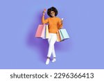 Small photo of Cool stylish happy smiling young black woman with bushy hair wearing sunglasses holding colorful shopping bags, smartphone, bank card, posing over purple studio background. Unlimited shopping