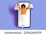 Small photo of Pretty cheerful young black woman in casual with bushy hair shopaholic standing over big phone with white empty blank screen, smiling, carrying shopping bags, purple background, copy space