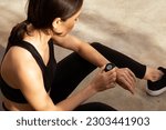 Small photo of Tired millennial european woman athlete in sportswear checks pulse on fitness tracker in city, outdoor. Result body care, cardio training and fitness, gadget for active workout
