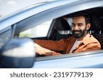 Own auto. Handsome indian guy driving car enjoying road trip, looking at vehicle mirror, side view shot. Bearded Arabic Driver Guy Posing In Automobile With Opened Window Inside
