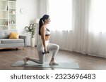Small photo of Full body dumbbell workout at home. Strong attractive slim well-fit young woman wearing white sportswear exercising with dumbbells, standing on fitness mat, copy space, living room interior