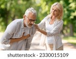 Small photo of Senior man suffering from heart attack while walking with wife in park, mature male having sudden pain in chest, feeling unwell oitdoors, worried woman supporting husband. Healthcare and insurance