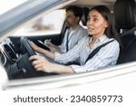 Scared unconfident young woman driving car with instructor man by her side. Lady driving school student passing exams test, looking at road with frightened face expression. Fear of driving