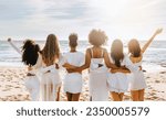 Small photo of Back view of multiracial ladies in white dresses posing on beach and looking at ocean, having maiden evening, hen party outdoors. Group of women embracing