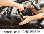 Small photo of Hands of valet parking worker giving key to driver man sitting inside car. Unrecognizable man buyer taking key from brand new automobile at autosalon showroom. Car buying, renting