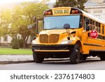 Shot of retro-styled yellow school bus with extended red stop sign standing still on serene road, empty vehicle with no driver awaiting children to boarding, transportation concept, copy space