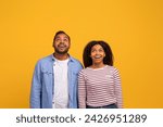 Small photo of Portrait Of Amazed Young Black Couple Looking Up With Opened Mouth, Dazed African American Man And Woman Emotionally Reacting To Big Sale Or Nice Offer, Standing Over Yellow Background, Copy Space