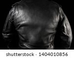 Photo of a man in black leather biker jacket standing on neon lightened night street background rear view.