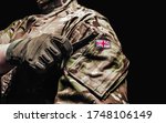 Photo of a british soldier in multicam camouflage tunic using pocket on black background.