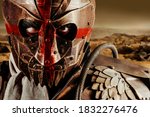 Small photo of Photo of a post apocalyptic raider warrior in leather jacket with metal armor and steel mask with red cross painting standing in desert wasteland.