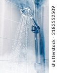 Small photo of contrast shower with flowing water and steam, blue background