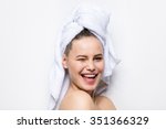 close-up of beautiful young woman with bath towel on head covering her breasts, on white