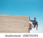 Man hanging on cement wall