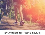 Woman's legs with backpack walking across hanging bridge (intentional vintage color and sun glare)