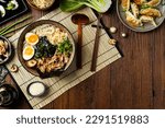 Small photo of Traditional ramen with jerked pork or chicken. With udon or ramen noodles. Served in classic bowls. Gyoza dumplings and mushrooms in the background. Natural wooden background.