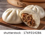 Delicious baozi, Chinese steamed meat bun is ready to eat on serving plate and steamer, close up, copy space product design concept.