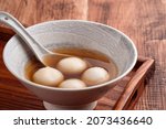 Small photo of Close up of sesame big tangyuan (tang yuan, glutinous rice dumpling balls) with sweet syrup soup in a bowl on wooden table background for Winter solstice festival food.