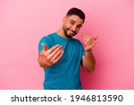 Small photo of Young mixed race man isolated on pink background pointing with finger at you as if inviting come closer.