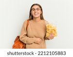 Small photo of Young student Indian woman holding crips isolated on white background laughing and having fun.