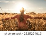 Small photo of Young woman sitting in meadow taking in the beauty and warmth of the sun