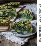 Small photo of Homemade rectangular Spinach quiche made with spinach green dough, with mozzarella cheese, buttermilk cream and black sesame seeds, garnished with leaves cut from the same dough over wooden surface