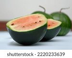 half of a ripe, red, small watermelon on a light background, cut watermelon
