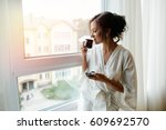 A girl in a bathrobe drinking coffee in the morning on the windowsill.