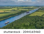 Aerial view of Kiel Canal with container ship and  traditional sailing vessel.Container cargo ship and tall ship on the Kiel Canal between Baltic sea and North Sea Schleswig Holstein, Germany.