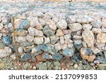 Small photo of Stone walls, protection from backshore erosion. Stones in a metal mesh. Gabion wall constructed using steel wire mesh basket. Steel gabion filled with granite rocks at river bank.