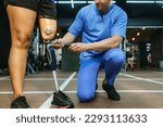 Small photo of Physiotherapist take care patient and prosthetic leg of her. Physiotherapist helping disabled Woman with prosthetic leg in sports center. Rehab and gym with physiotherapists and patient work together