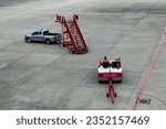 Small photo of Airplane tow tractor at the airport apron near the terminal. Aircraft Towing Tractor. A towing tractor belonging in air port is being operated by officer. Aerodrome tow tractor is driving at airport