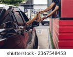 Small photo of Hand Man in car receiving coffee in drive thru fast food restaurant. Staff serving takeaway order for driver in delivery window. Drive through and takeaway for buy fast food for protect covid19.