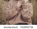 Closeup of woman wearing a beige soft oversized knitted sweater or jumper outdoors in the nature. Autumn fall scenery