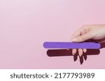 Small photo of female hand filing nails polish on pink background. Concept of lady painting, polishing nails. Nail brush, nail polish, nail file. Spa treatment beauty. Flat lay with copy space.