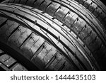 Studio shot of a set of summer car tires isolated on black background. Tire stack background. Car tyre protector close up. Black rubber tire. New car tires. Close up  tyre profile. Car tires in a row