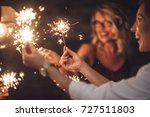 Group of happy people holding sparklers at party and smiling.