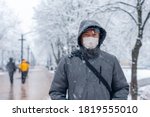 Portrait of a man wearing a medical protective mask on his face in winter, Covid-19 coronavirus pandemic, virus protection.