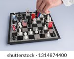 Small photo of Politician's hand moves a chess piece with a flag. Conceptual photo of a political game. retaliatory move Russia