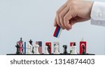 Small photo of Politician's hand moves a chess piece with a flag. Conceptual photo of a political game. retaliatory move Russia