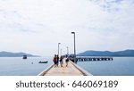 Small photo of Group of Asian friends walking on concrete pier to go aboard a ship, seascape and mountain background, Group travel concept
