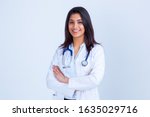 Medical concept of Indian beautiful female doctor in white coat with stethoscope, waist up. Medical student. Woman hospital worker looking at camera and smiling, studio, gray background